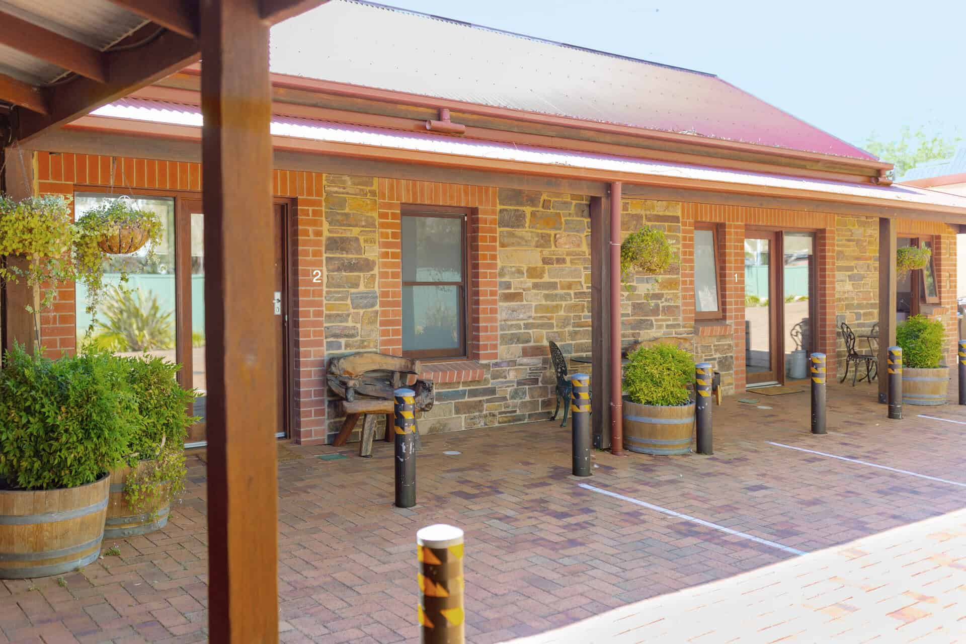Courtyard walkway outside motel rooms with seating and potted plants.