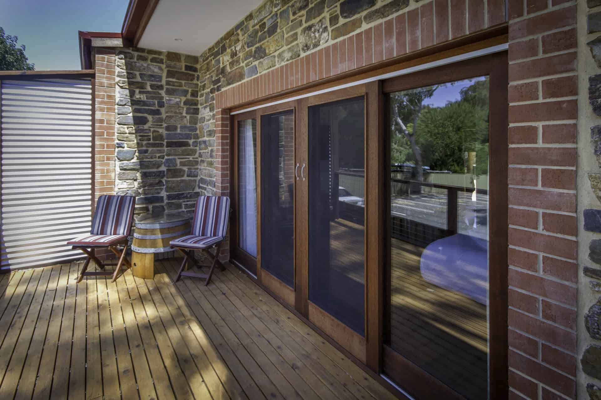 Large sliding doors leading out to outdoor balcony with wooden decking and seating area.